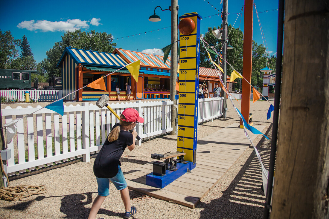 Youn visitor testing her strength in Games Alley at the Midway