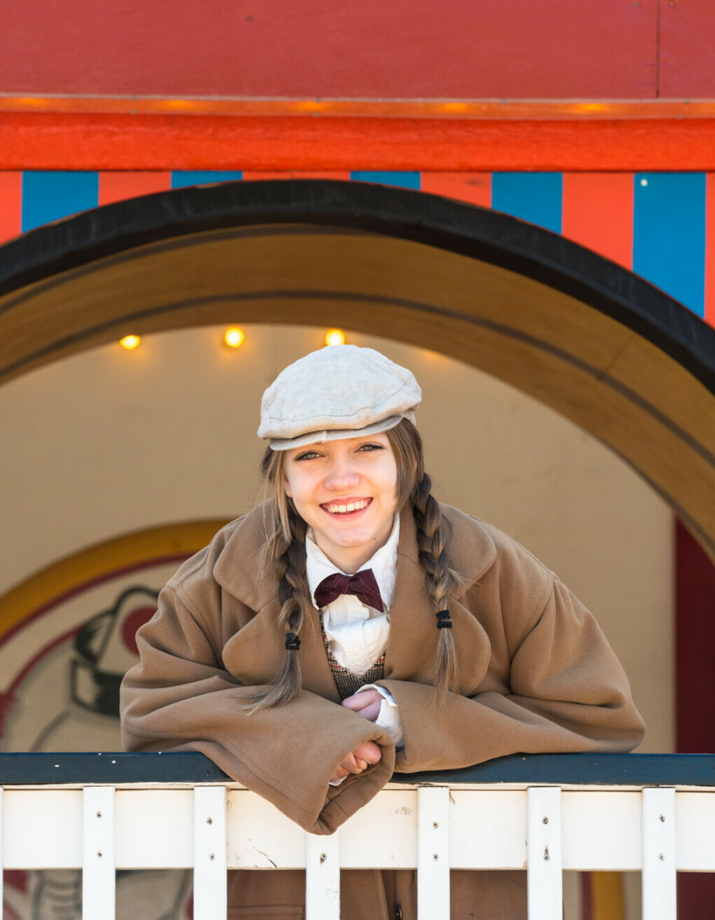 Female costumed interpreter leaning on Midway Funhouse railing